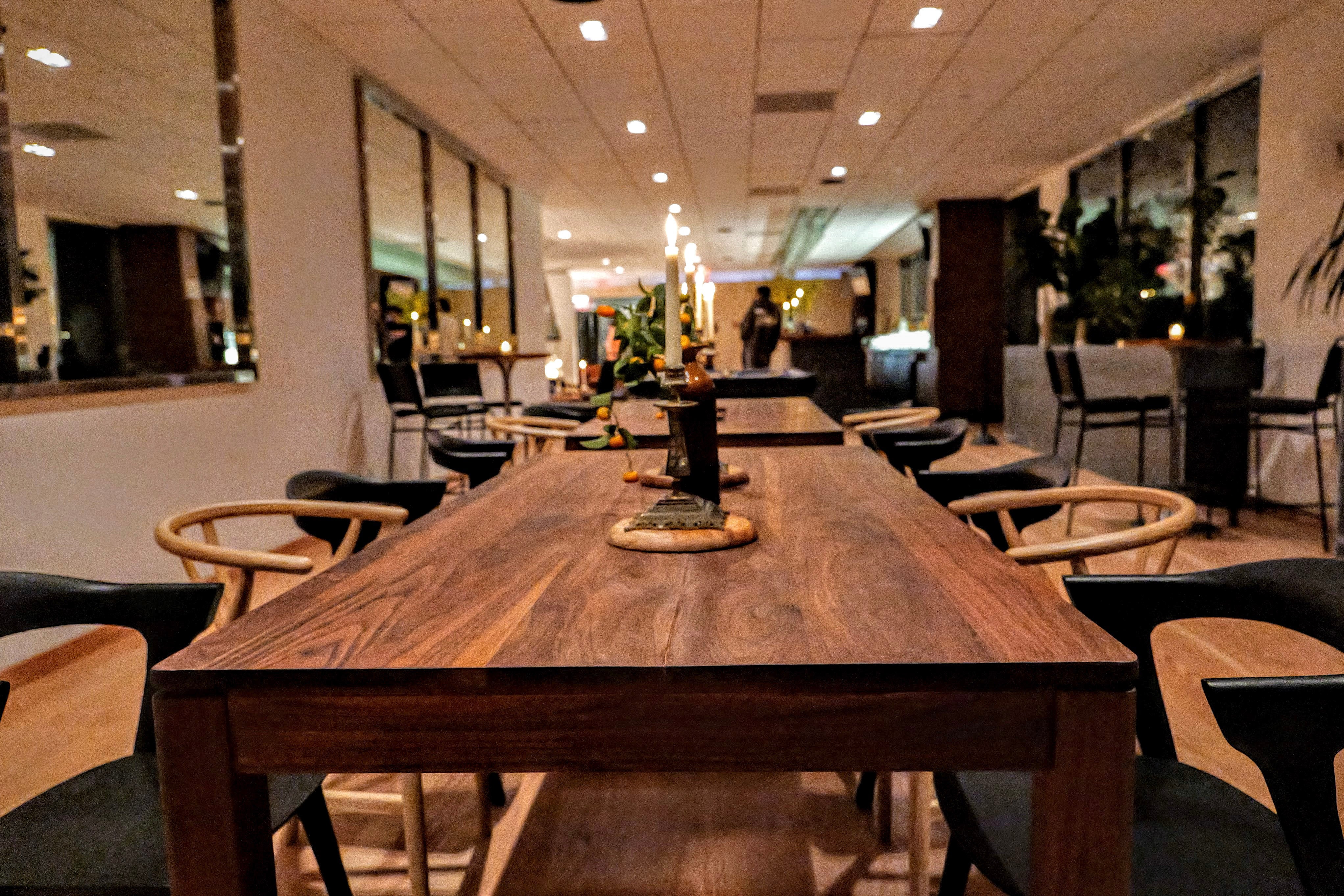 Long communal walnut table in the CityView members lounge under pendant lighting