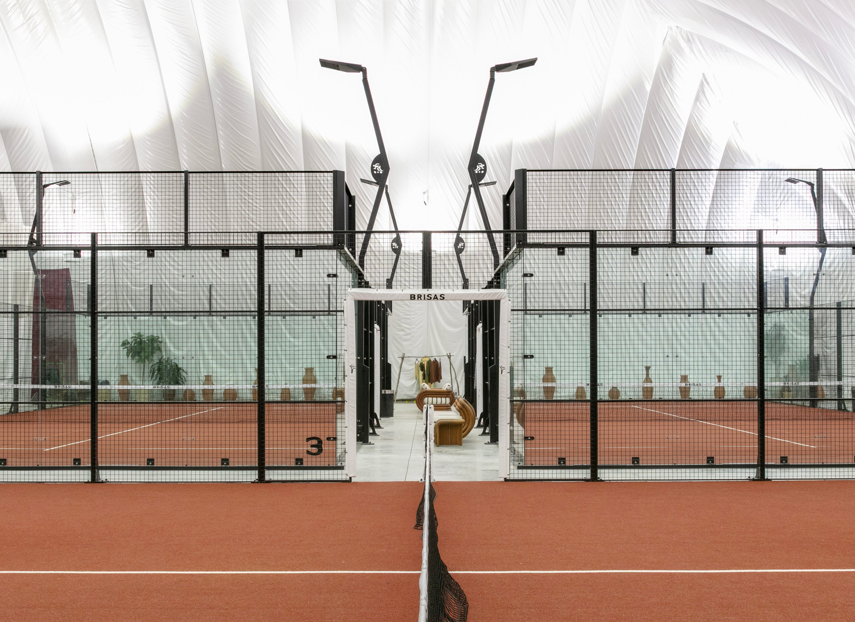 Padel courts at CityView, glass walled with terracotta clay surface, under the fabric bubble